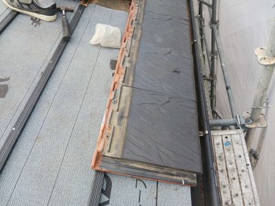 岐阜市K様邸の天窓撤去跡地。新設された野地板（木の板）の上に、灰色の防水シート（ルーフィング）が隙間なく敷き詰められている。その上に、もともと使用されていた平板瓦「セラムF3」が、新しい防水対策が完了した証として並べられ始めている。