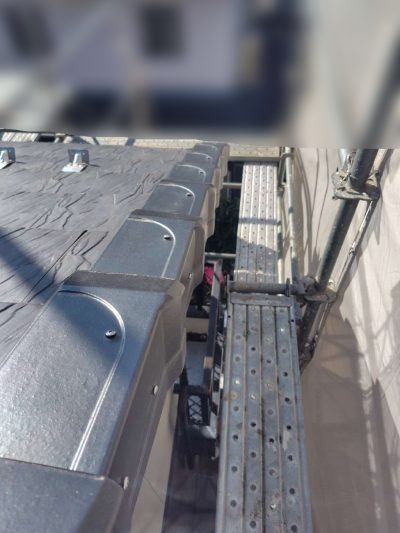 岐阜市K様邸の屋根修理完了後の袖瓦（ケラバ）部分。浮き上がっていた袖瓦が、新しい水切り板金の上に真っ直ぐ美しく並べ直され、現代の防災基準でしっかりと固定されている。背景には点検用の足場が見える。