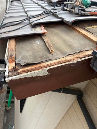 屋根のケラバ（袖瓦）周辺を部分解体し、雨水で黒く腐食してボロボロになった木下地が露出している様子