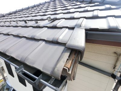 屋根のケラバ修理の施工前写真。脱落した瓦の隙間から雨水が侵入し、茶色い破風板の木部が変色して傷んでいる様子