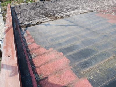 岐阜市H様邸の屋根カバー工法（施工中）。太陽光温水器（天日）を撤去した後のスレート屋根の様子。天日の跡が黒く残り、周囲は経年劣化で赤茶けている状態