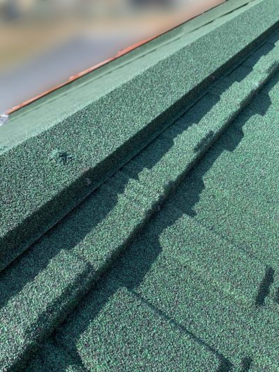 岐阜市H様邸の屋根カバー工法施工中。雨漏りの原因になりやすい棟部（屋根の頂点）にTルーフ専用の同質棟役物（グリーン）を取り付けている様子